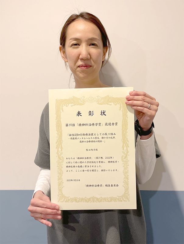 表彰状を持つ蟹江絢子客員研究員の写真